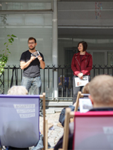 Scena na ul. Quadro, widzowie siedzą na leżakach. Na scenie dwie osoby.