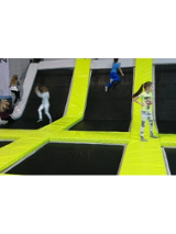 Dzieci na trampolinach oddzielonych żółtymi materacami.