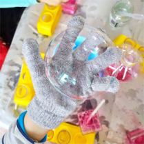 W dłoni w rekawiczce kula przeźroczysta pod dłonią wazoniki i inne pojemniki.