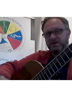 Męszczyzna gra na gitarze. Po lewej logo Przystani Artystycznej.