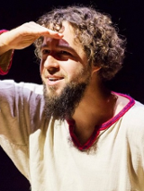 Karawany Opowieści: uśmiechnięty, ubrany w białą płócienną koszulę aktor wypatruje czegoś w oddali.