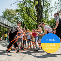 Grupa dzieci na dworze i 2 opiekunów bawią się gumą.