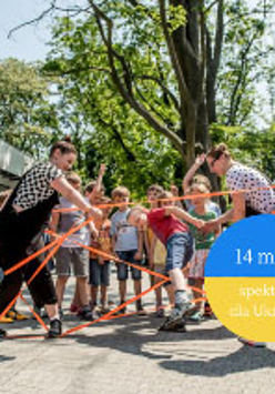 Grupa dzieci na dworze i 2 opiekunów bawią się gumą.