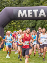 biegacze podczas biegu na tle bramy startowej z napisem start