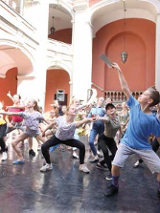 Wychowankowie szkoły baletowej tańczą na dziedzińcu szkoły.