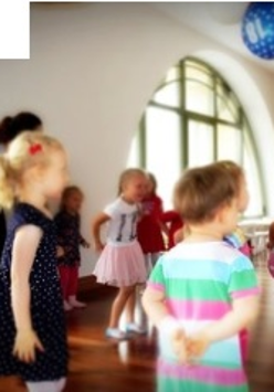 Częściowo nieostre zdjęcie z zajęć Strefa Zabawy. Roztańczone dzieci bawią się pod troskliwą opieką instruktorki.