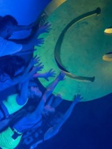 Na grafice kilka osób dotykających wyciągniętymi rękoma uśmiechniętą bużkę (emotikon).