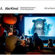 Na zdjęciu widać grupę dzieci i dorosłych siedzących tyłem, na poduszkach na podłodze, oglądających wyświetlany film animowany. Na pierwszym planie filmu jest mały biały miś.