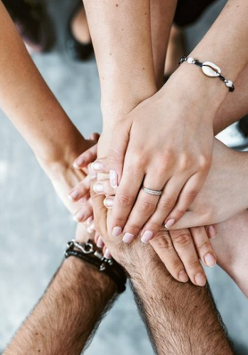 Ręce wielu osób, które nakładają się jedne na drugie.