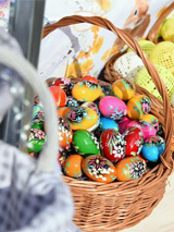 Kolorowe jajka w koszykach wiklinowych na straganie.