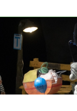 na zdjęciu dwie lalki teatralne: starszy pan stoi po lewej stronie, starsza pani po prawej, pomiędzy nimi wózek dziecięcy. Nad lalkami widoczne ręce aktorów.