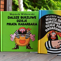 Trzy ksiązki stojące obok siebie z kolorowymi okładkami z piratem. W tle zielone drzewa.