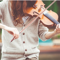 Młoda kobieta gra na skrzypcach wśród przyrody.