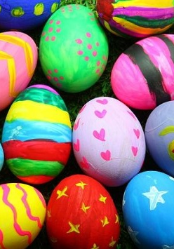 Kolorowe pisanki leżą na trawie.