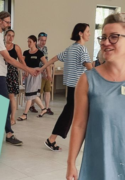 Kilkanaście osób trzymajacych sie za ręce, które ida jaden za drugim