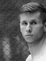 Czarno-białe zdjęcie przedstawia twarz tancerza Daniela Michny, patrzącego wprost w kierunku, z którego wykonano zdjęcie.