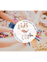 Logo Kids Club. Na stole kulki i koraliki oraz dłonie dzieci uczestniczących w zajęciach. Na srodku białe koło z napisem kids klub.
