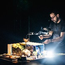 Mężczyzna pochyla się nad oświetloną makietą.