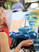 Kobieta przed sztalugą, maluje obraz.