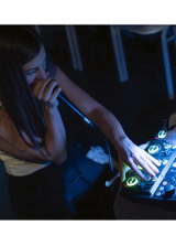 Na zdjęciu młoda dziewczyna siedzi przy konsoli didżejskiej, w ręce trzyma mikorofon, coś mowi.