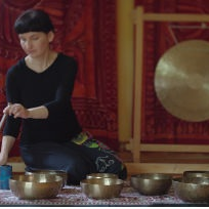 Kobieta gra na misach ustawionych na podłodze. Na ścianie wisi gomg.