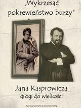 Brodaty mężczyzna z założonymi rękoma stojący przed obrazem wiszącym na ścianie.