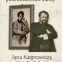 Brodaty mężczyzna z założonymi rękoma stojący przed obrazem wiszącym na ścianie.