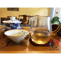 Na stole biała czarka do herbaty, cukiernica i szklany dzbanek z herbatą