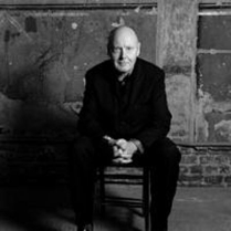 Paul McCreesh siedzi na stołku przy murze