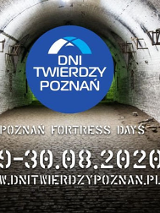 Fort od srodka. Ściany i sklepienie z cegeł. Na środku logo imprezy: białe litery na niebieskim tle.