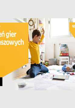 Na zdjęciu chłopiec i prawdopodobnie jego tata siedzą na podłodze i grają w planszówki. Po lewej w pomarańczowej ramce biały napis "Dzień gier planszowych".