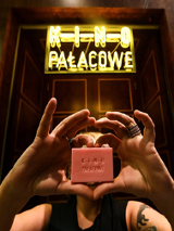 Kobieta trzyma w rękach małe różowe mydło z napisem: Kino Pałacowe. Nie widać jej twarzy. Nad nią neon kinowy.