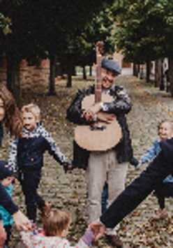 Pięć osób, dwie kobiety i dwoje dzieci, po środku mężczyzna obejmujący gitarę.