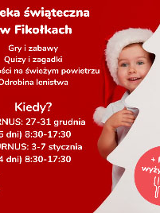 Dziecko w czapce św. Mikołaja wygląda zza choinki.
