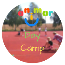 Kolorowy napis "Animar - Day Camp", na rozmazanym tle grupa dzieci na boisku.