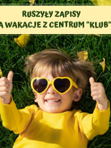 Dziecko leży na trawie w ciemnych okularach w kształcie srduszek.