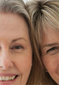 Dwie uśmiechnięte kobiety stykają się głowami.