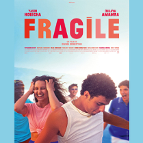 Na pierwszym planie młody chłopak o ciemnych włosach, za nim stoi roześmiana dziewczyna, w tle grupa młodych osób. Czerwono-pomarańczowy tytuł na jasnoniebieskim tle.