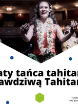 Tańczące na scenie kobiety w kwiecistycych strojach. Na dole napisy.