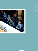 Dziei ogladające prezentacje multimedialne w sali muzealnej.