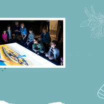 Dziei ogladające prezentacje multimedialne w sali muzealnej.