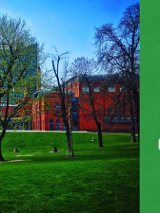 Po lewej zielony park przy Starym Browarze, a po prawej stronie baneru białe napisy na zielonym tle.