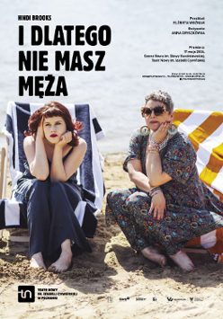 Dwie kobiety - jedna młoda, druga strasza - ubrane w sukienki, siedzą na leżakach na plaży. Obie z poważnymi minami patrzą przed siebie.