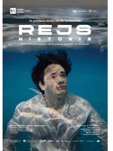 Zdjęcie mężczyzny zanurzonego pod wodą w basenie, ma ciemne włosy, ubrany jest w białą koszulę, patrzy przed siebie