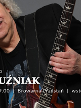 Zdjęcie Piotra Kuźniaka trzymającego gitarę na szarym tle. Na froncie napisy. Szczegóły dotyczące wydarzenia zawarte w treści artykułu.
