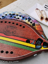 Na stole leżą dwie kolorowe paletki do tenisa plażowego.