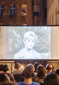 Taras kina Muza a na nim seans silent cinema. Przed widownią ekran z wyswietlanym filmem, widzowie w słuchawkach.