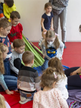 Dzieci na dywanie i pani prowadząca zajęcia.