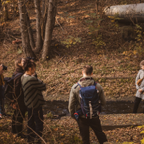 Grupa osób w lesie obseruje przyrodę.