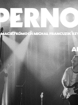 Czarno-białe zdjęcie z koncertu zespołu Supernova. Artyści występują na scenie, grając na instrumentach.